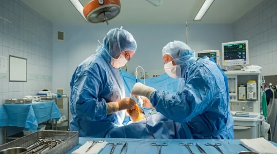 Chirurgien orthopédiste en tenue stérile préparant une intervention percutanée mini-invasive sur un pied dans une salle d'opération moderne, instrumentation spécialisée visible au premier plan